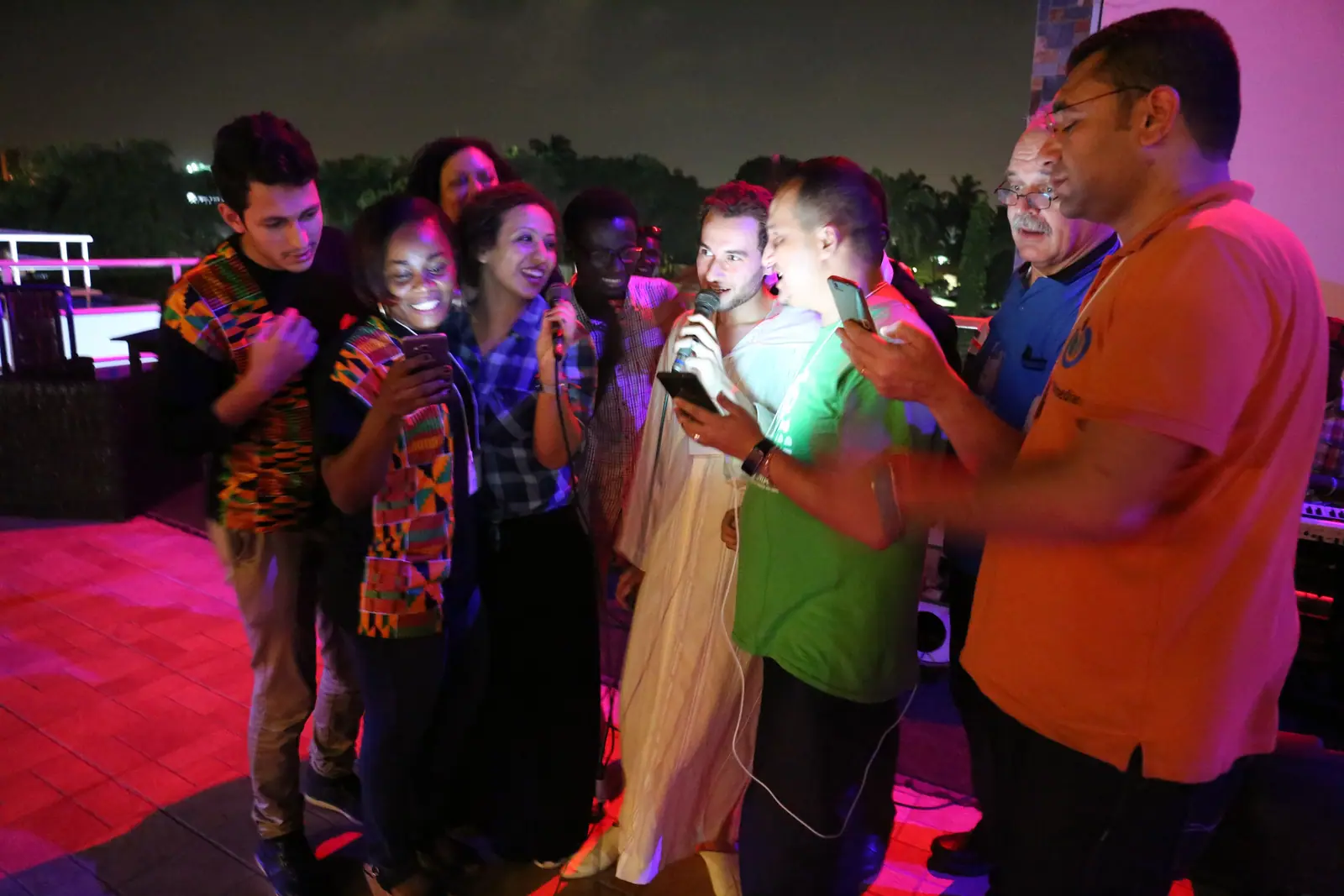 A group singing under neon lights, the mood a company dinner KTV KL night aims for (stock photo, not a specific venue)