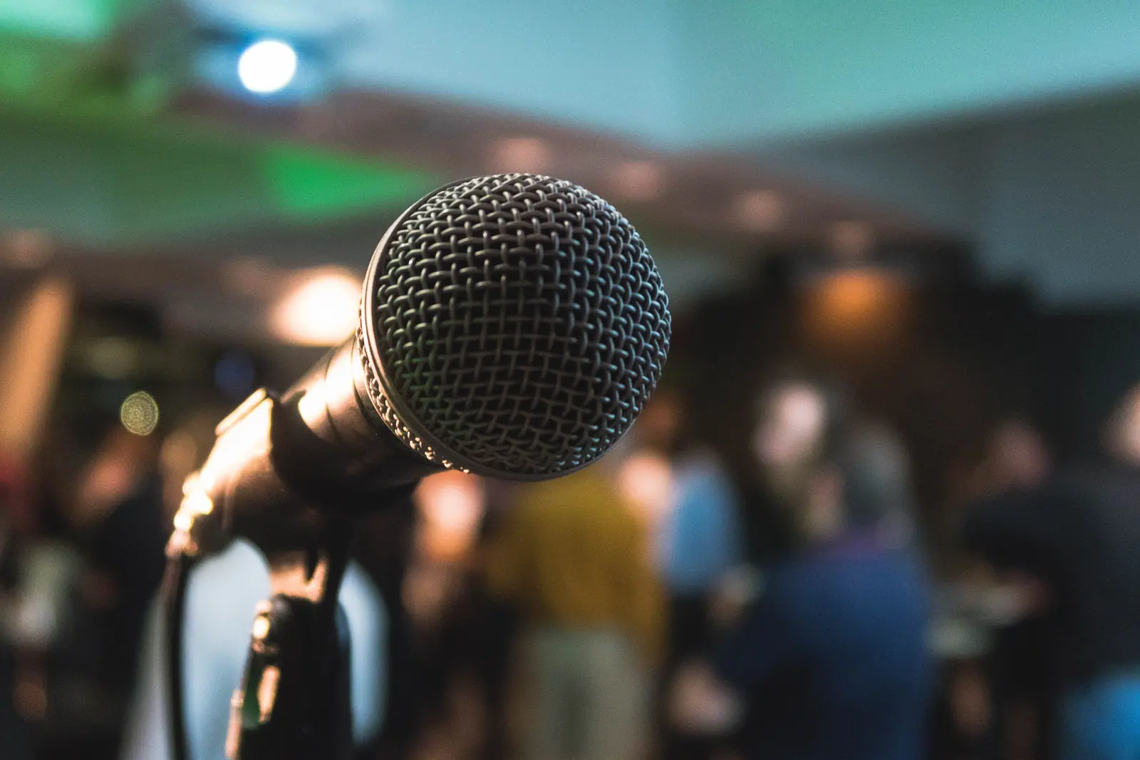 Illustrative photo, not Bintang Palace: Microphone on a stand in the foreground, blurred crowd and bar lights behind (karaoke night at a bar, not a private room)