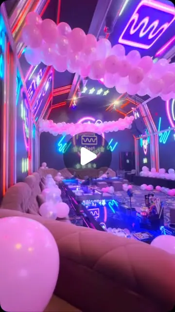 De-Millionaire KTV (富豪城): KTV room set up for a birthday with pink balloon garland and neon lights (reel frame, play icon overlay)